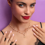 Woman wearing a gold necklace with a purple background