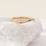 Gold ring with colorful stones on a white stone surface
