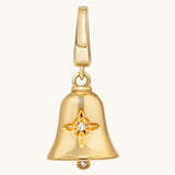 Close-up of a gold bell charm with a Witch’s Knot engraved on its polished surface on a ight cream background.