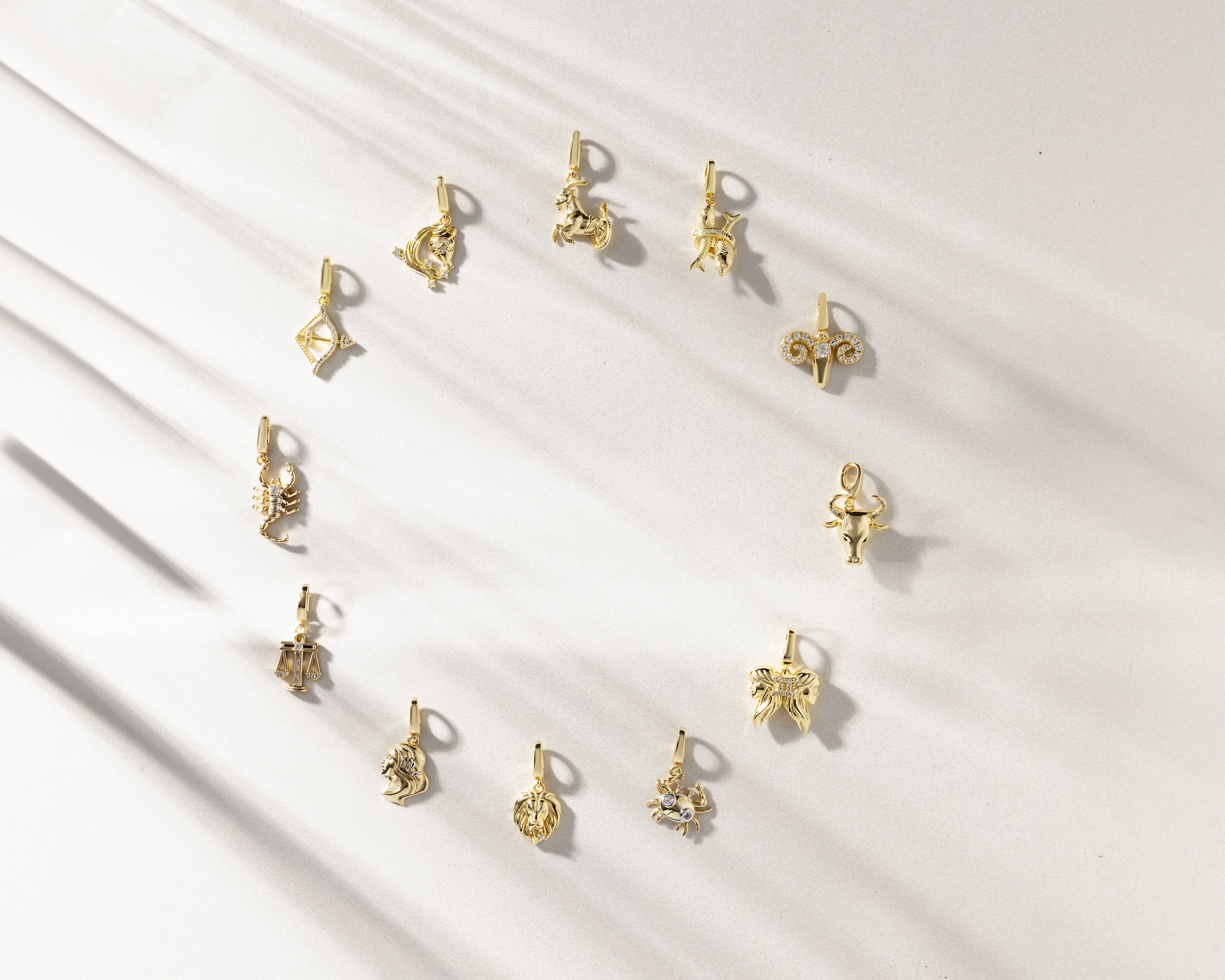 Gold zodiac charms on a white background