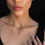 Woman wearing a gold crescent moon necklace, gold pentacle stud earrings, and a gold Triquetra ring with an intricate design.