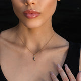 Woman wearing a gold crescent moon necklace, gold pentacle stud earrings, and a gold Triquetra ring with an intricate design.
