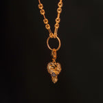 Preorder: Odin Charm (Ships end October 2026)—a gold chain necklace with a textured link and detailed heart pendant featuring two birds, inspired by Norse mythology, shown on a dark background.
