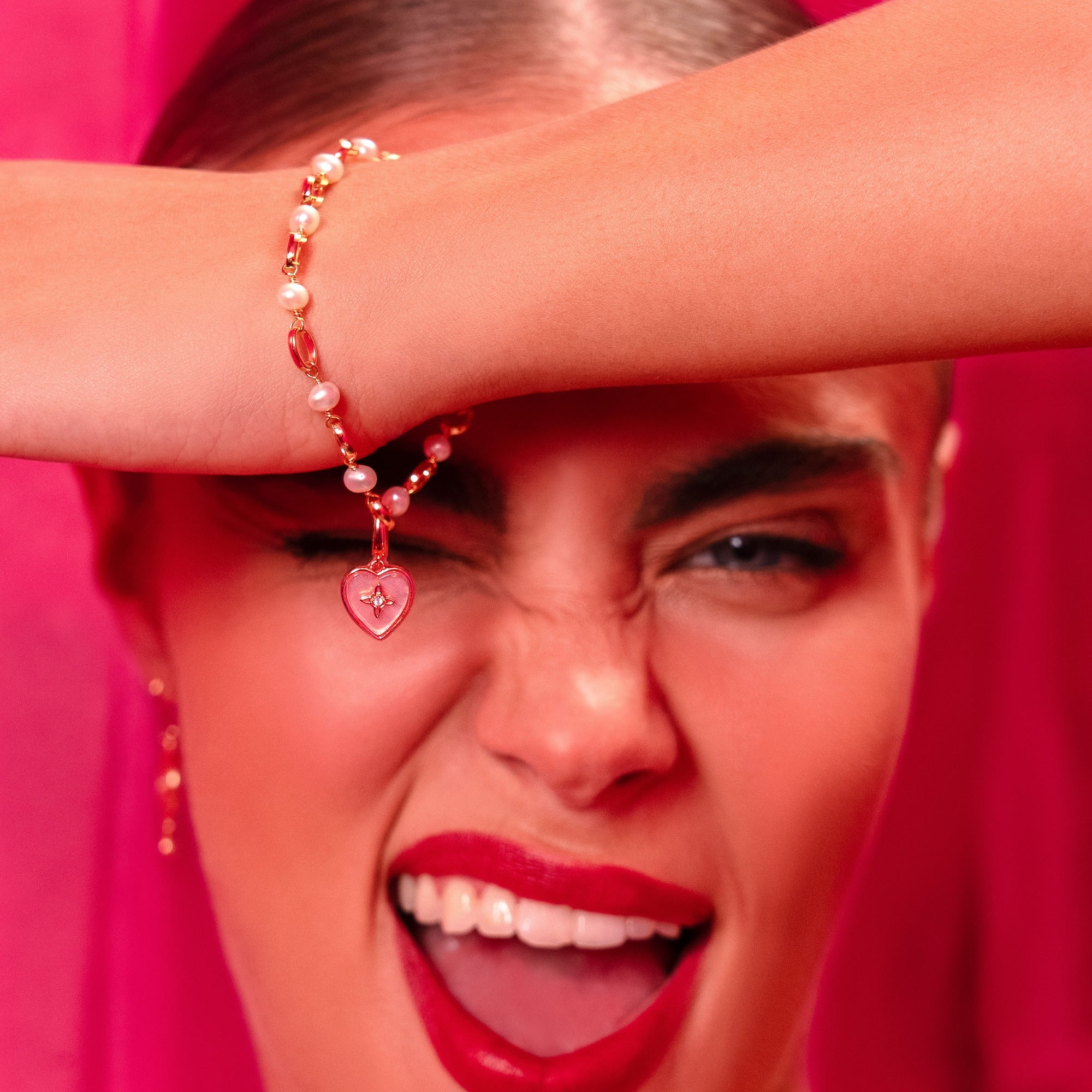 Close-up of a person with a pink background, wearing a bracelet.