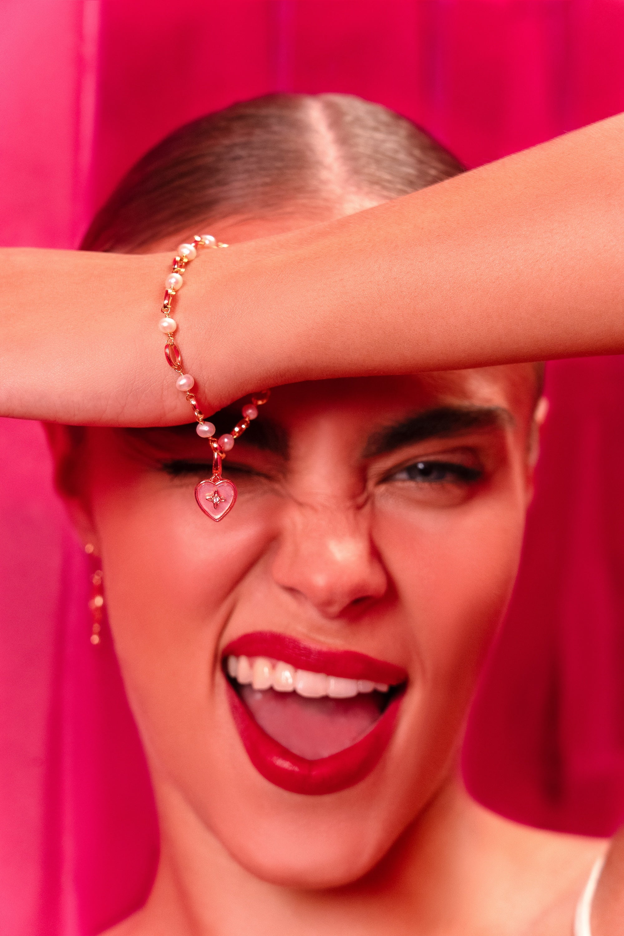 Close-up of a person with a pink background, wearing a bracelet.