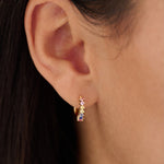 Close-up of an ear wearing a small earring with multicolored stones.