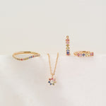 Set of gold jewelry with colorful stones on a light beige background