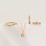 Set of gold jewelry with colorful stones on a light beige background