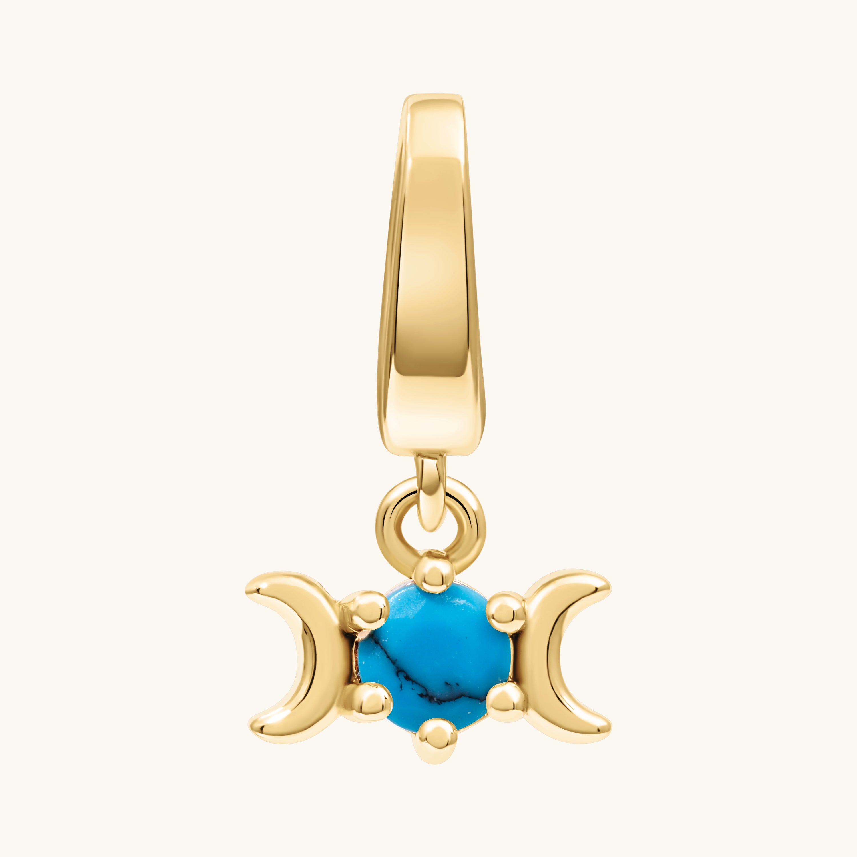 A gold triple moon charm pendant featuring a central turquoise blue stone, set against a plain off-white background.