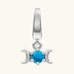 A sterling silver triple moon charm featuring a central turquoise cabochon stone, set against a plain off-white background.