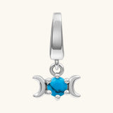 A sterling silver triple moon charm featuring a central turquoise cabochon stone, set against a plain off-white background.