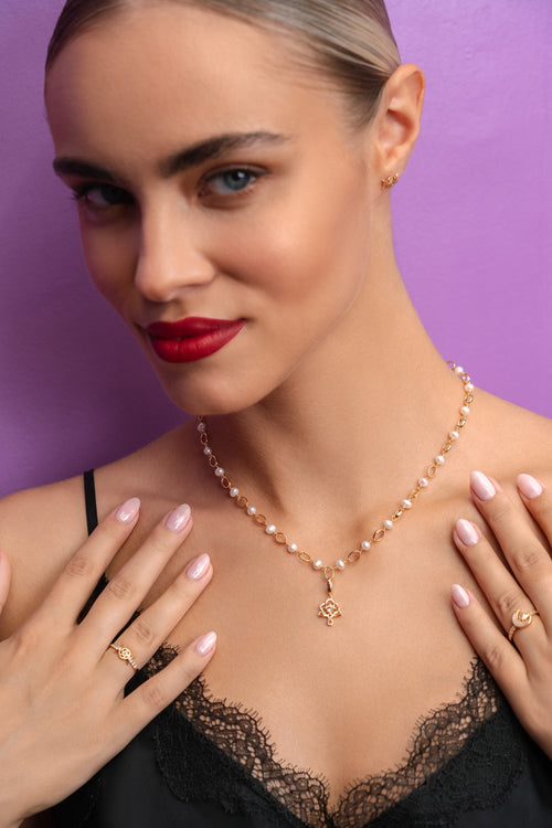 Woman wearing a pearl necklace with a purple background