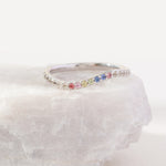Silver ring with colorful gemstones on a white stone surface