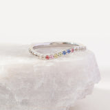 Silver ring with colorful gemstones on a white stone surface
