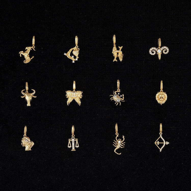 Collection of gold zodiac pendants on a black background