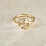 Gold ring with emerald stones on a beige background