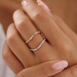 Close-up of a hand wearing two rings with colorful gemstones on a blurred background