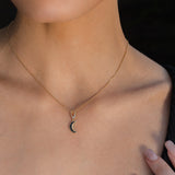 Woman wearing a gold crescent moon necklace, gold pentacle stud earrings, and a gold Triquetra ring with an intricate design.