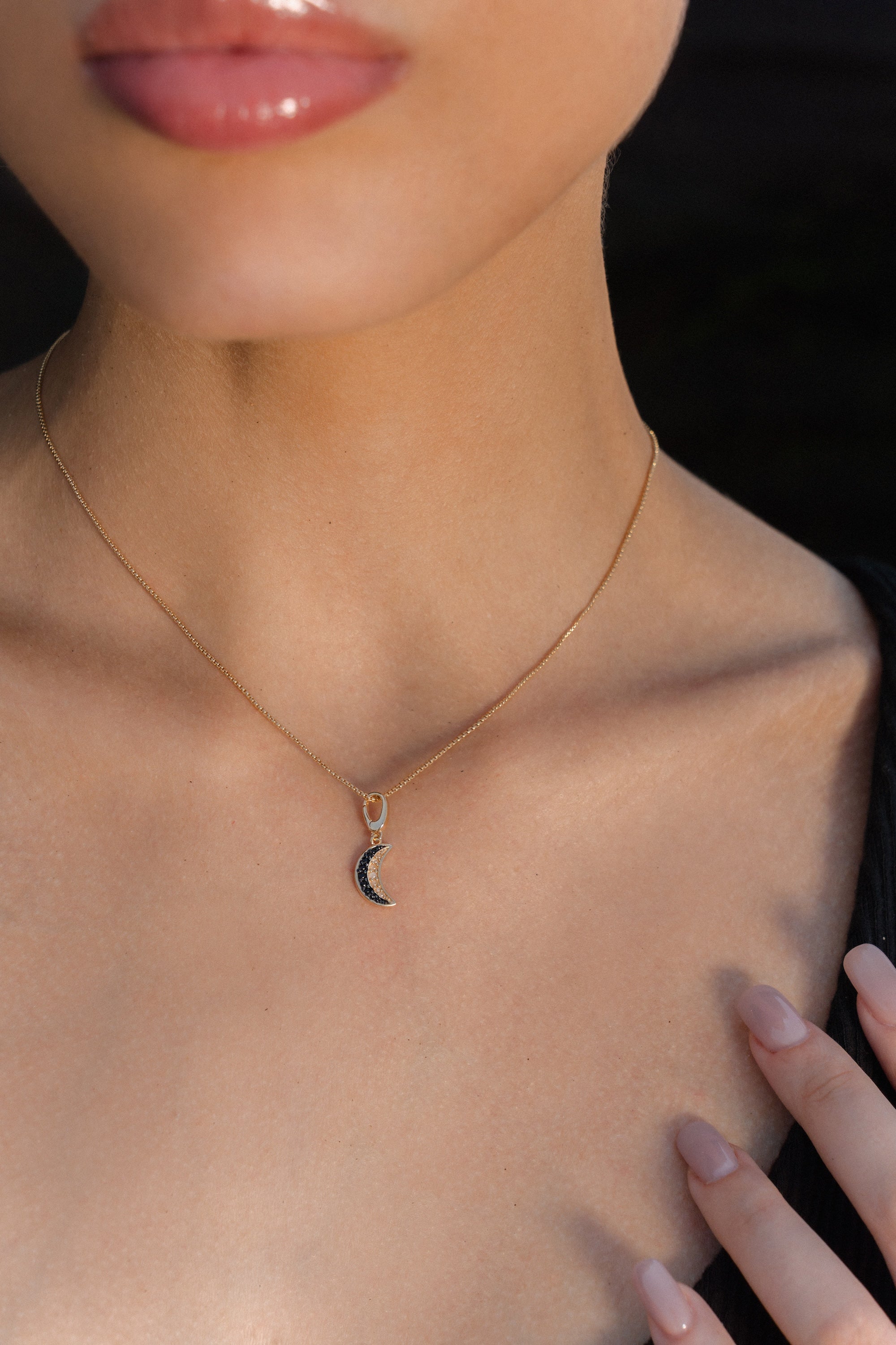 Woman wearing a gold crescent moon necklace, gold pentacle stud earrings, and a gold Triquetra ring with an intricate design.