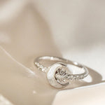 Silver ring with moon and star design on a white surface