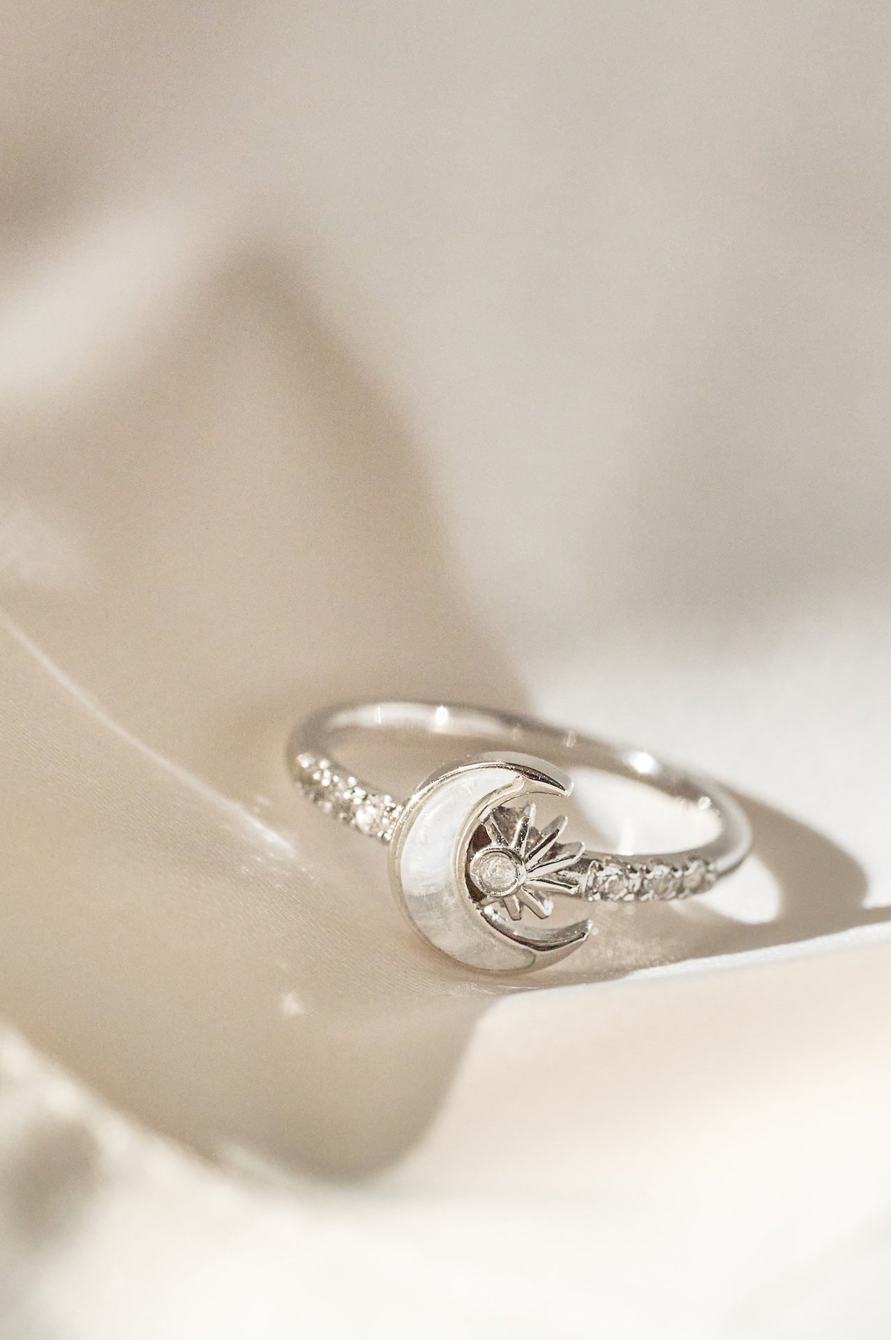 Silver ring with moon and star design on a white surface