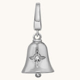 Close-up of a silver bell charm with a Witch’s Knot engraved on its polished surface on a ight cream background.
