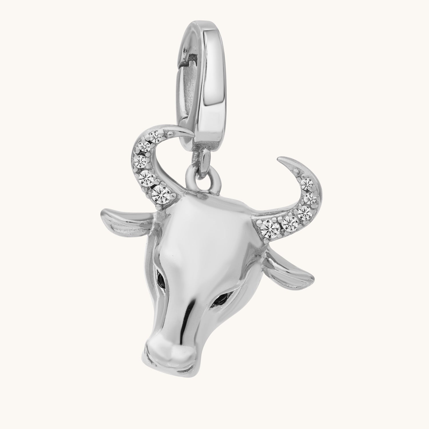 Silver bull head charm with crystal details on a white background