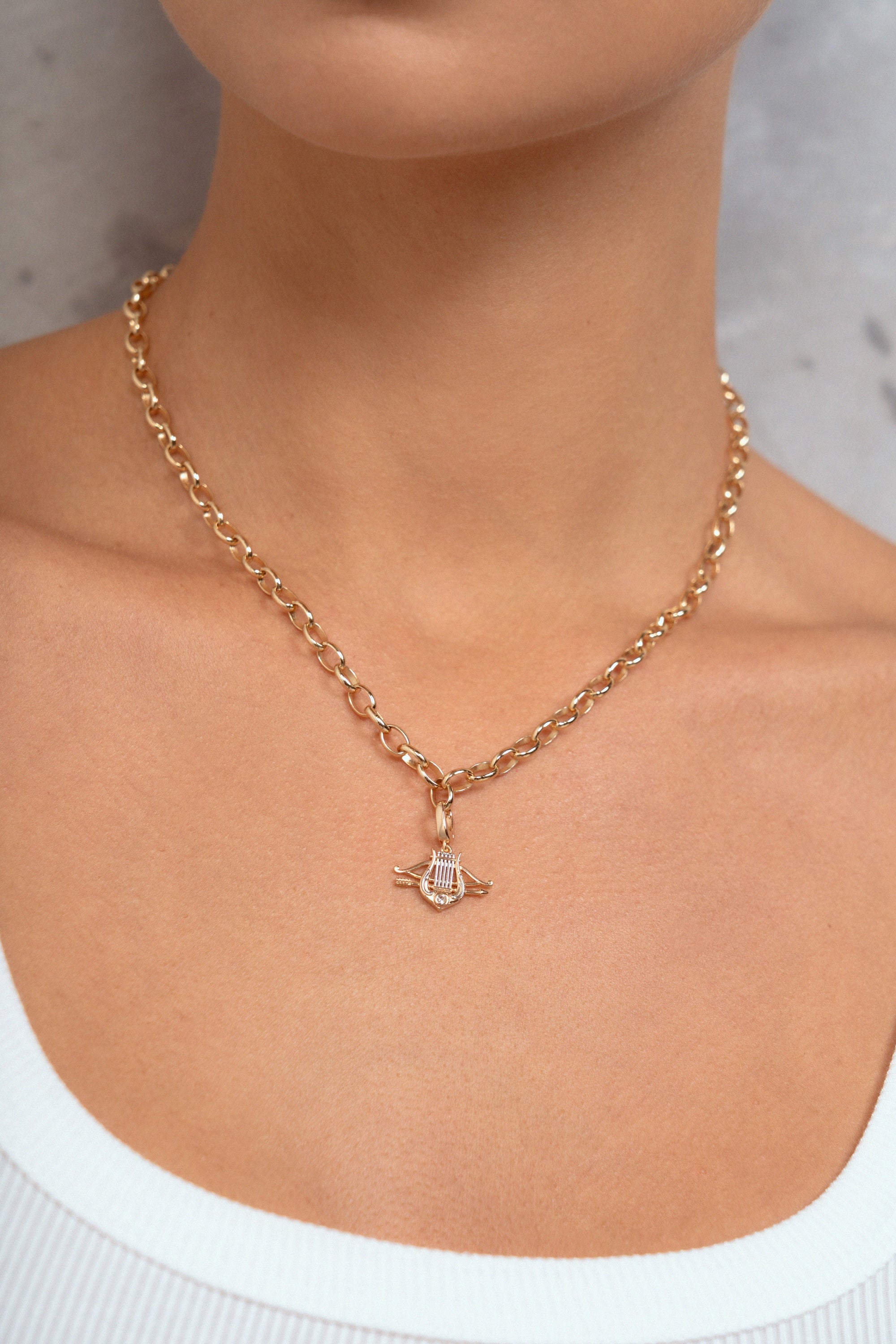 A close-up of a model wearing a delicate gold chain necklace with a small pendant featuring a clear central gemstone.
