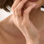 Close-up of a woman's hand with a gold ring near her lips.