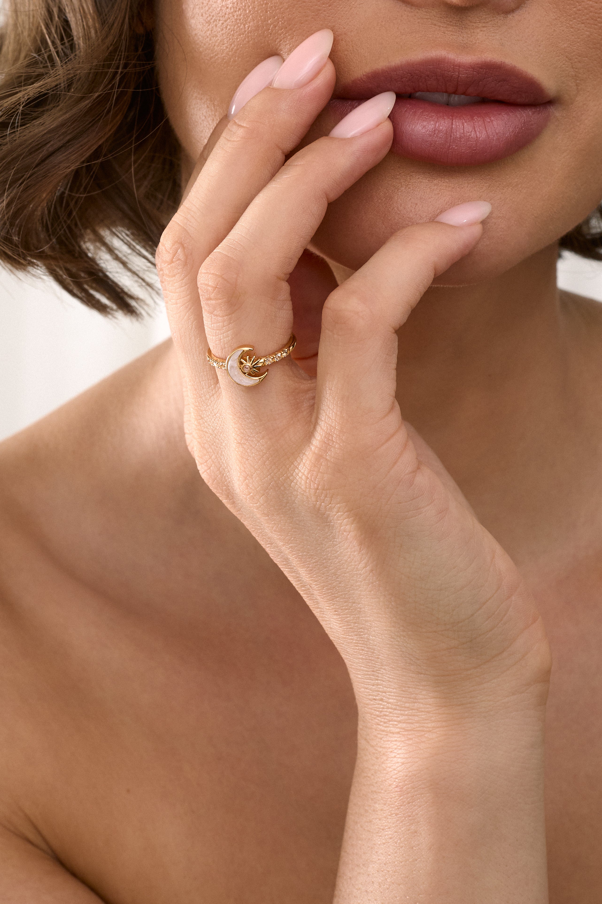 Close-up of a woman's hand with a gold ring near her lips.