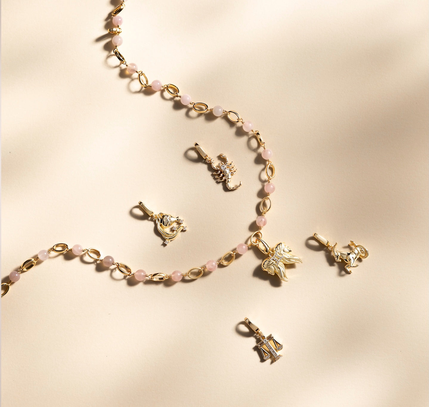 Gold necklace with various zodiac charms on a beige background