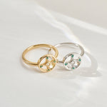 Two rings, one gold and one silver, with green gemstones on a white background