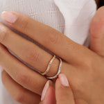 Close-up of a hand wearing two gold rings with gemstones on a white background