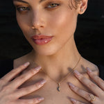 Woman wearing a gold crescent moon necklace, gold pentacle stud earrings, and a gold Triquetra ring with an intricate design.