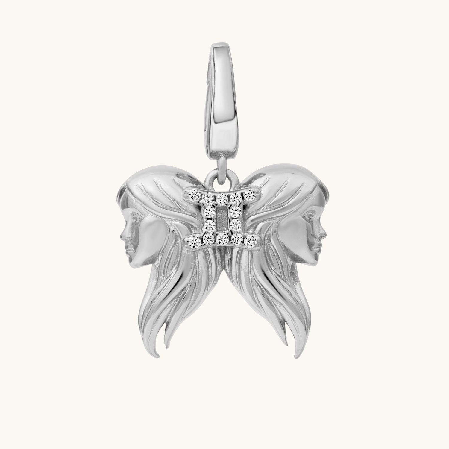Silver pendant with two female faces on a white background
