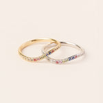 Two rings with colorful gemstones on a light beige background