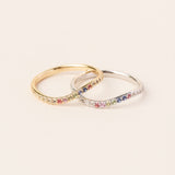 Two rings with colorful gemstones on a light beige background