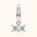 A silver-toned triple moon charm pendant featuring a central clear gemstone, set against a solid off-white background.