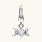 A silver-toned triple moon charm pendant featuring a central clear gemstone, set against a solid off-white background.