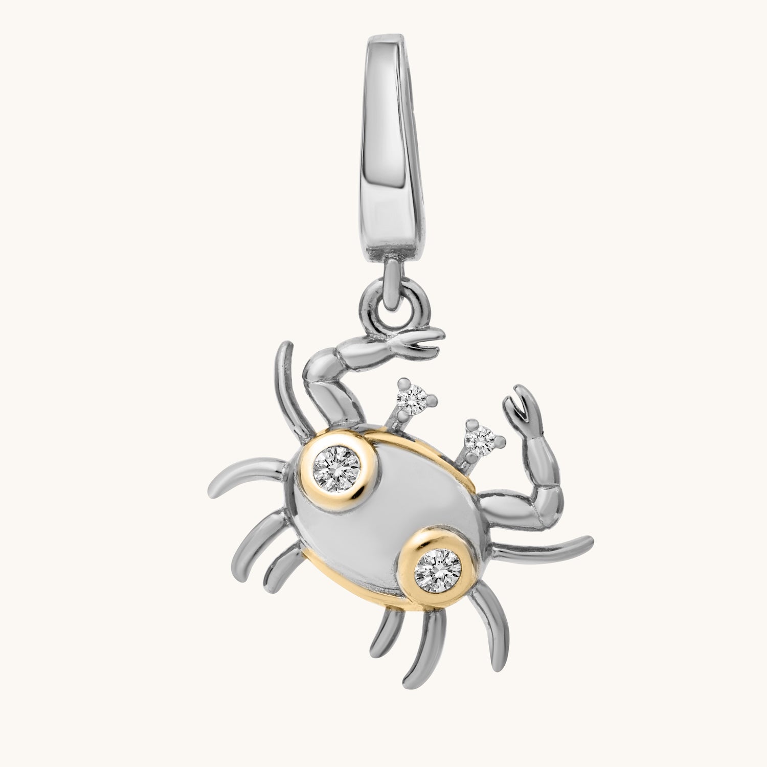 Silver and gold crab-shaped pendant with embedded stones on a white background