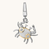 Silver and gold crab-shaped pendant with embedded stones on a white background