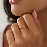 Close-up of a person's hand with a gold ring near their mouth.