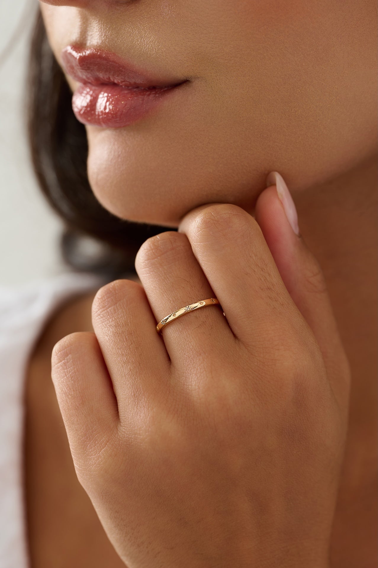 Close-up of a person's hand with a gold ring near their mouth.