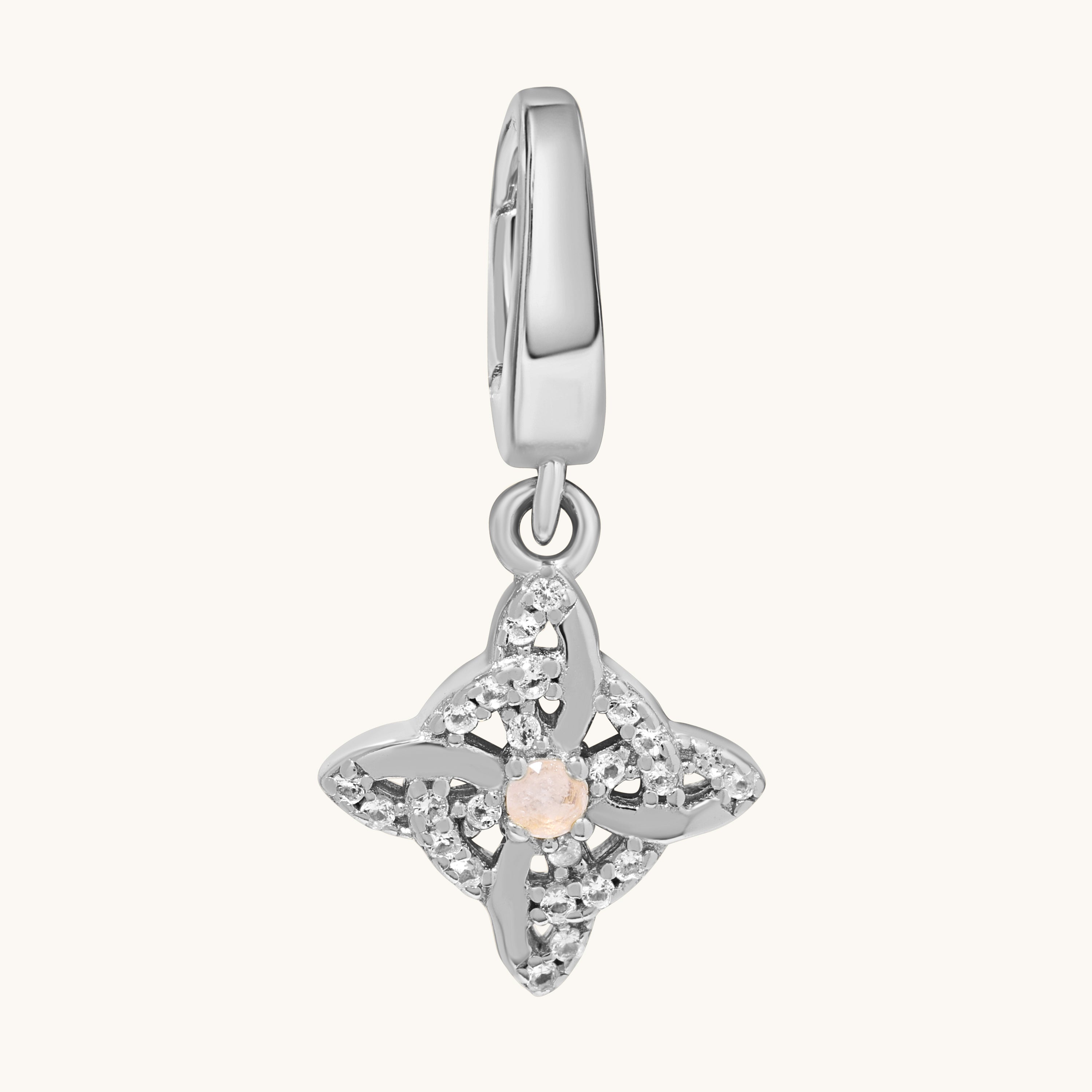 A silver-toned charm pendant featuring a central pale moonstone gemstone surrounded by clear white topaz stones, suspended from a matching silver bail, shown on a light cream background.
