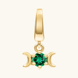 A gold triple moon pendant charm featuring a central round-cut green gemstone, set against a plain off-white background.