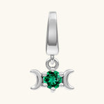 A sterling silver triple moon pendant charm featuring a central round-cut green gemstone, set against a solid off-white background.