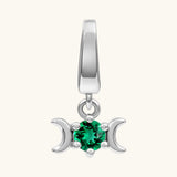A sterling silver triple moon pendant charm featuring a central round-cut green gemstone, set against a solid off-white background.