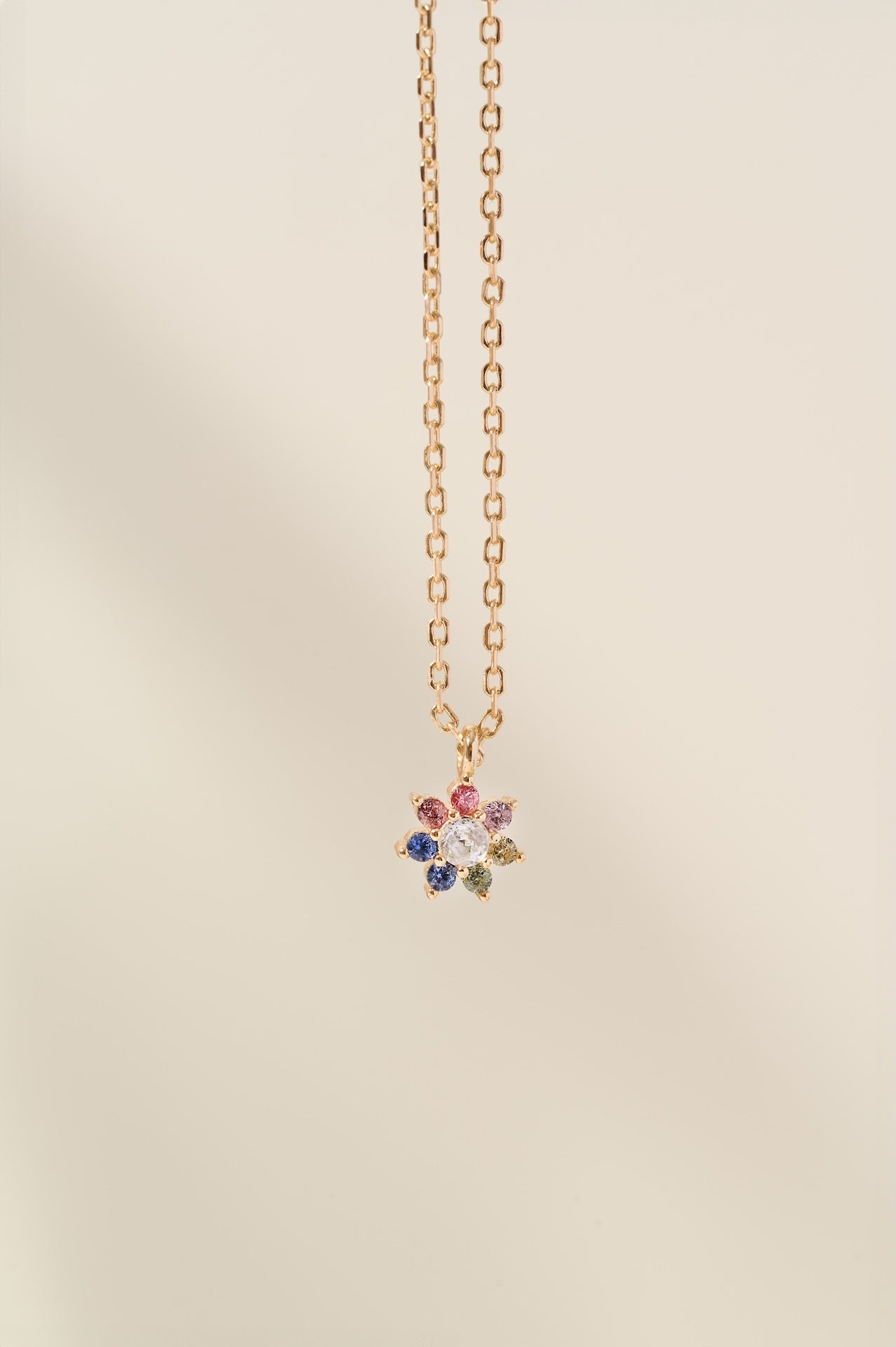 Necklace with a multicolored gemstone pendant on a beige background