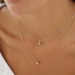 Close-up of a person wearing two delicate necklaces with small pendants.