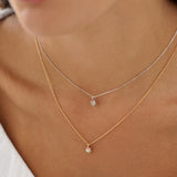 Close-up of a person wearing two delicate necklaces with small pendants.